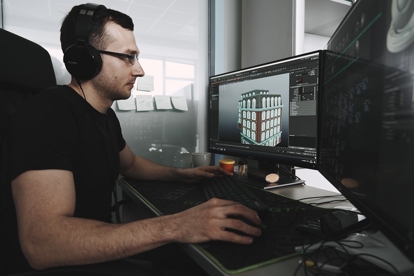 Home Uomo con cuffie lavora su modello 3D di un edificio al computer.